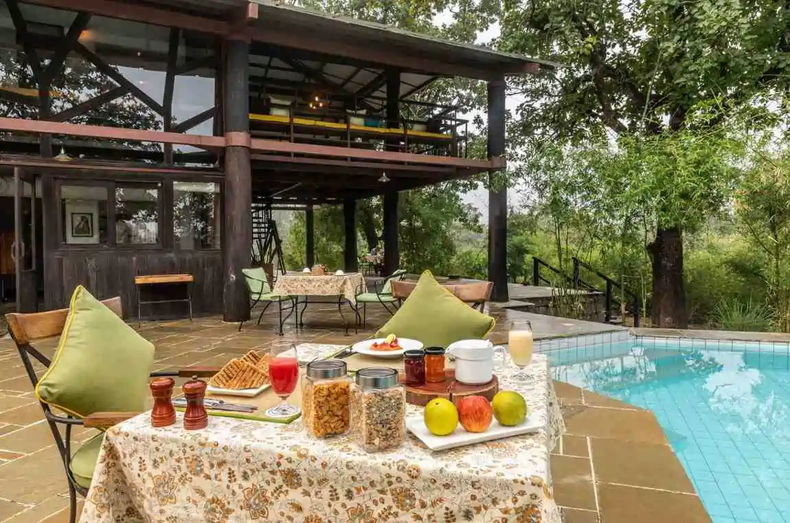 Outdoor dining setup beside the pool at Pench Tree Lodge